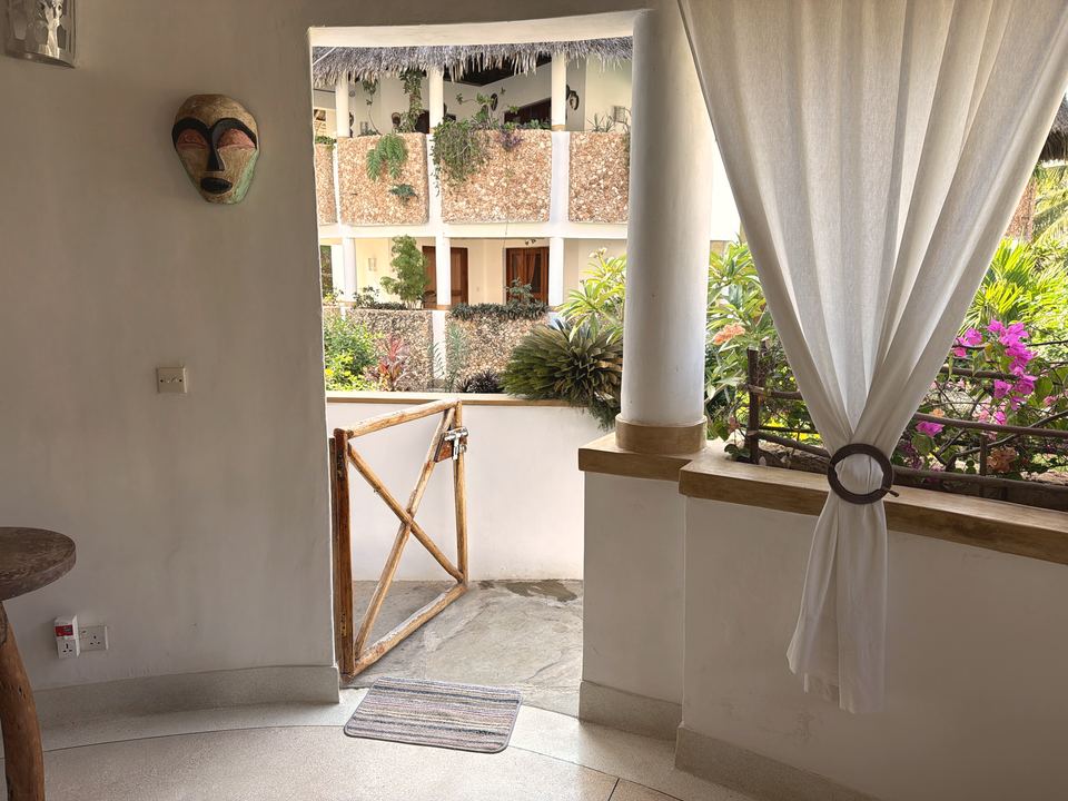 Ingresso con maschera alla parete e cancelletto in legno aperto sul village